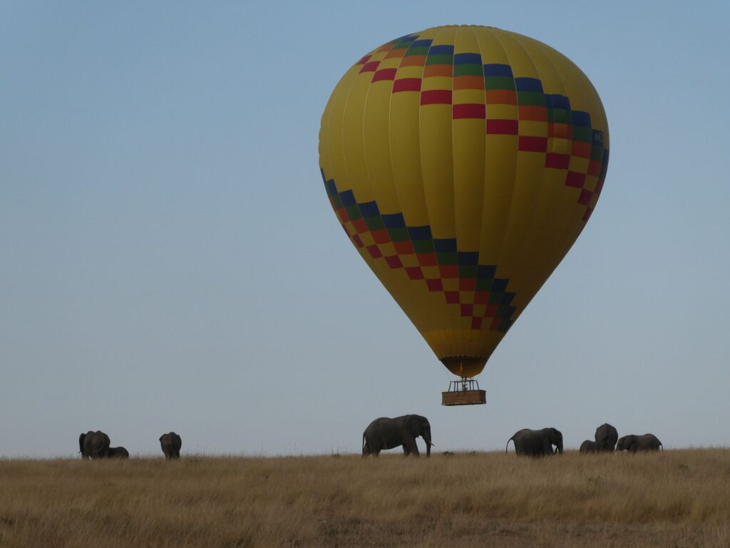 Hot air balloon floating above elephants on the Maasai Mara plains